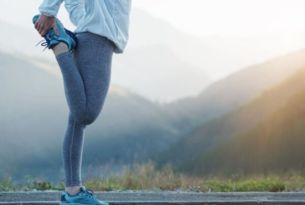Runner stretching a leg on a mountain road at sunrise