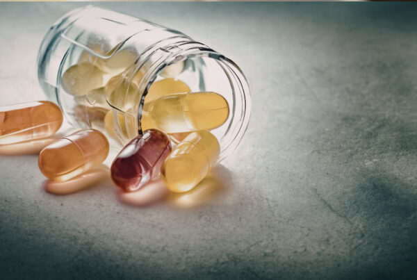 Assorted supplement capsules and pills spilling out of a jar