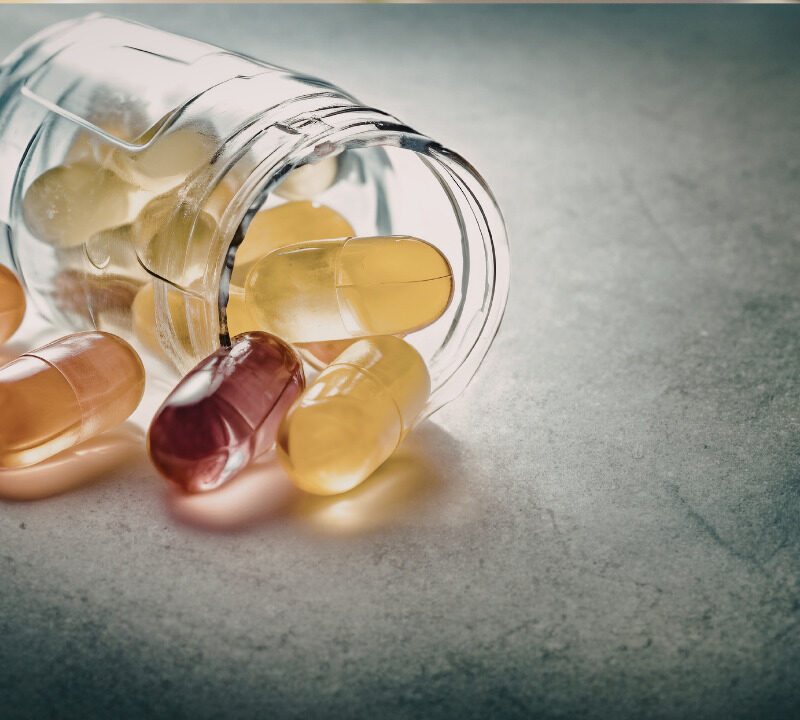 Assorted supplement capsules and pills spilling out of a jar