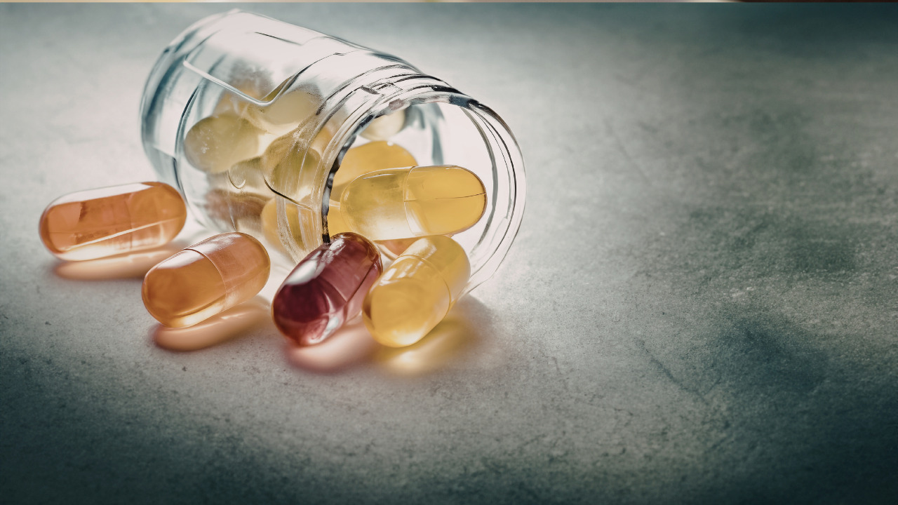 Assorted supplement capsules and pills spilling out of a jar
