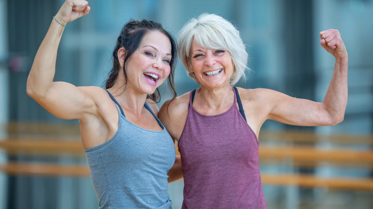 Two smiling women flexing their arm muscles