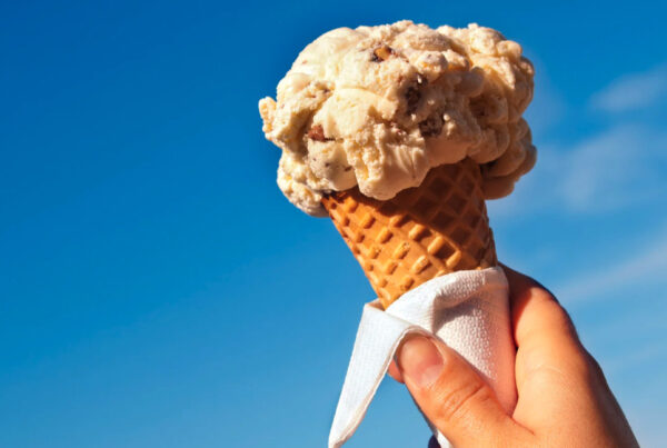 Smiling person holding a large ice cream cone