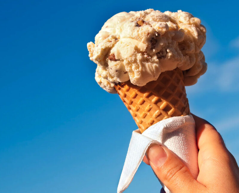 Smiling person holding a large ice cream cone