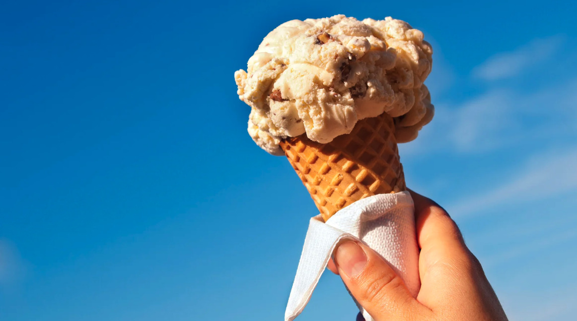 Smiling person holding a large ice cream cone