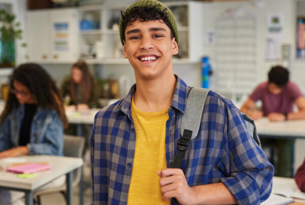 Smiling young man in a plaid shirt in a classroom