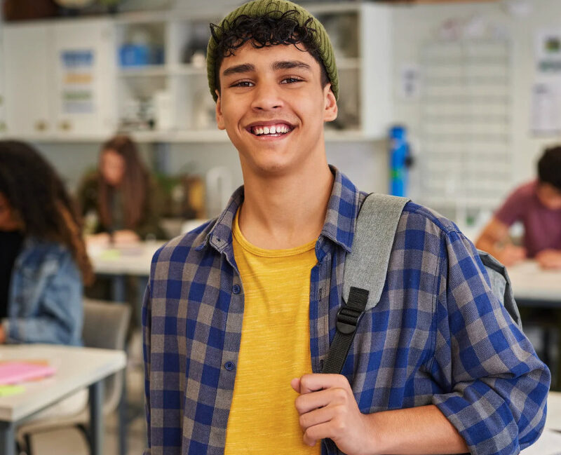 Smiling young man in a plaid shirt in a classroom