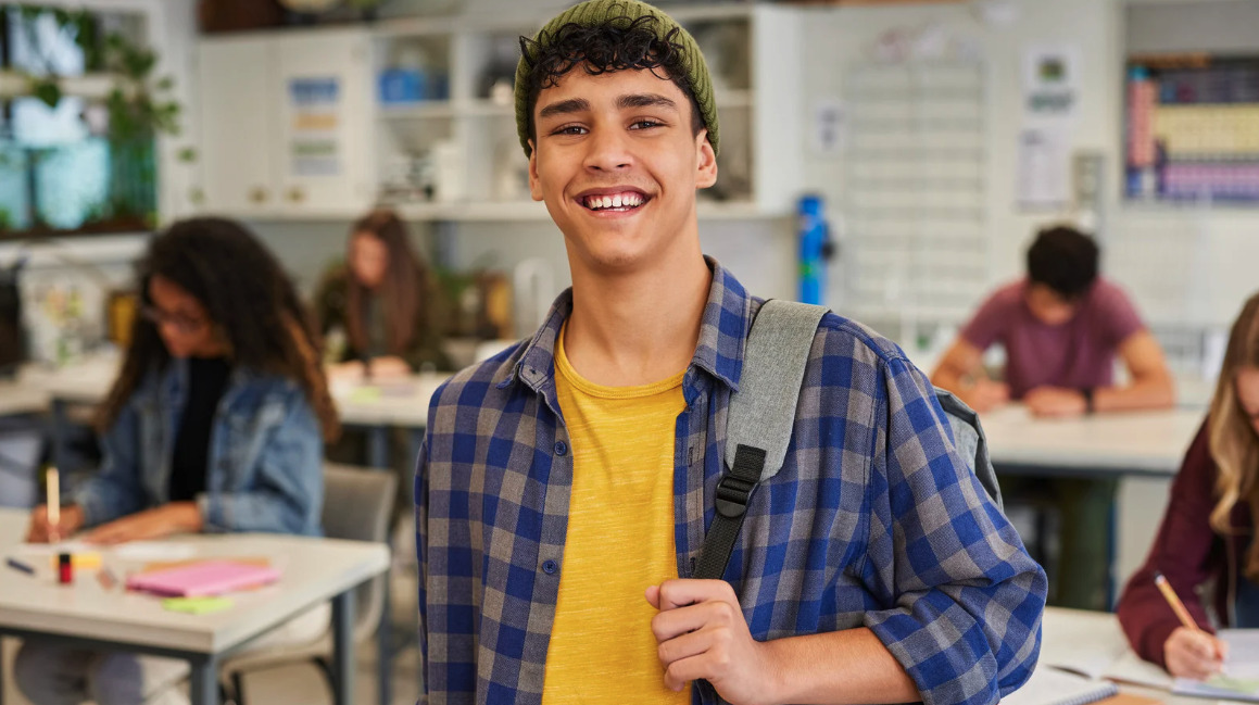 Smiling young man in a plaid shirt in a classroom