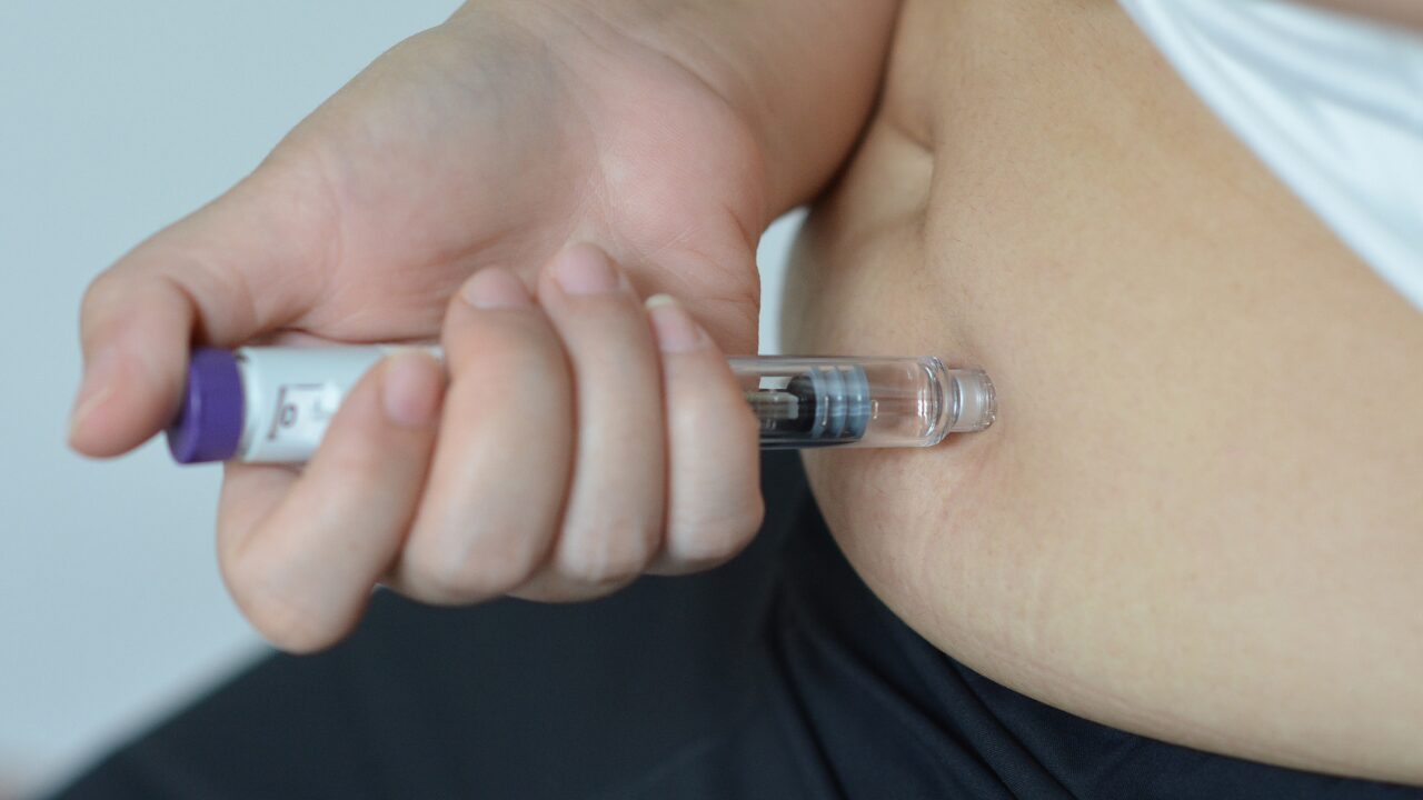 Woman injecting a GLP-1 weight loss medication into her abdomen