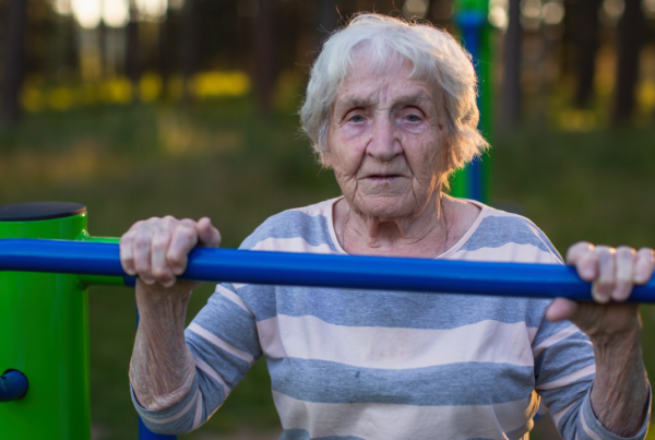 Older woman gripping an outdoor exercise bar