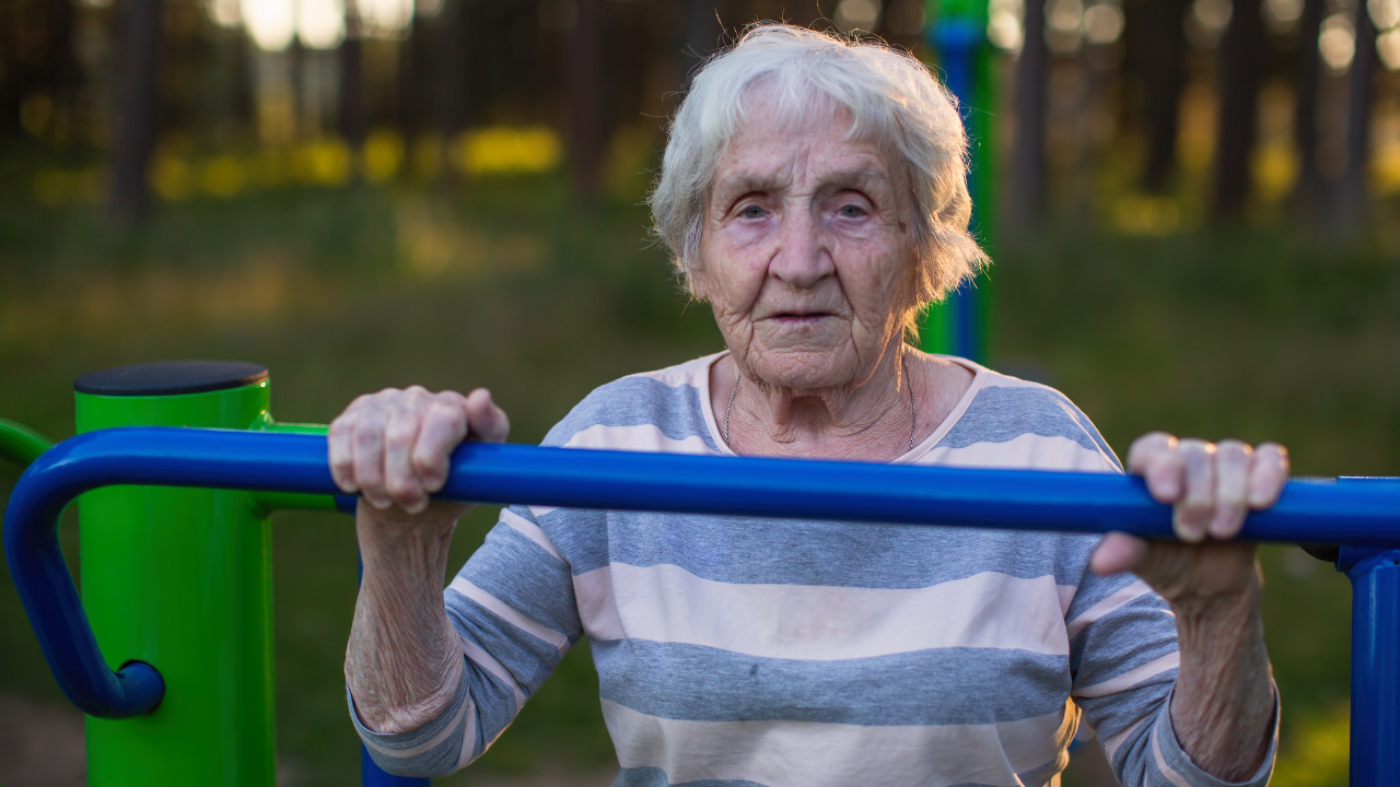 Older woman gripping an outdoor exercise bar